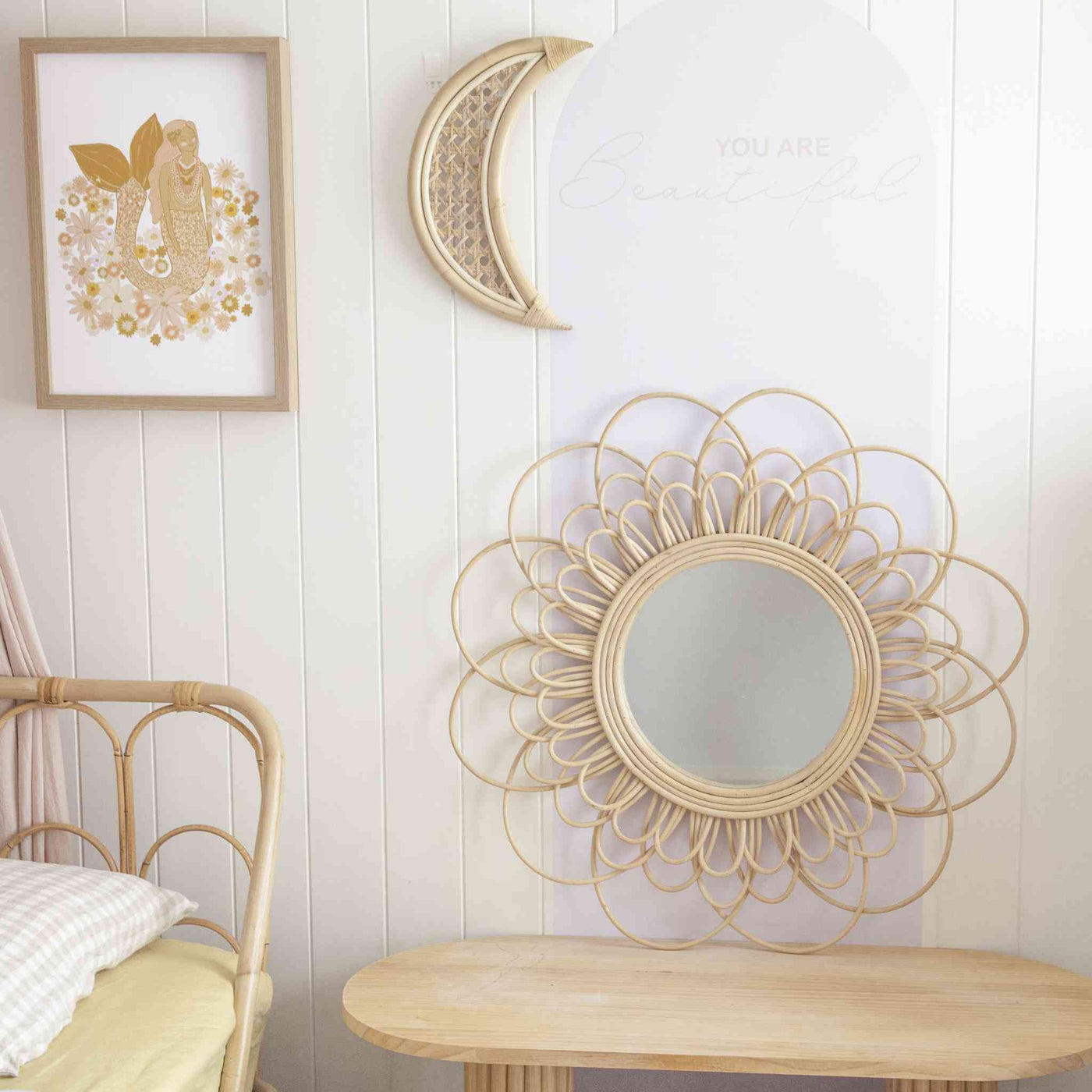 rattan flower mirror sitting on desk leaning against wall, paired with a rattan moon.