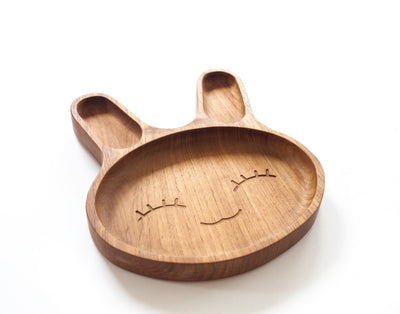 A Teak Plate for food seperation shaped as a bunny with a engraved face in the center, for kids 